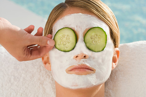 Woman with facial mask and cucumber slices over eyes